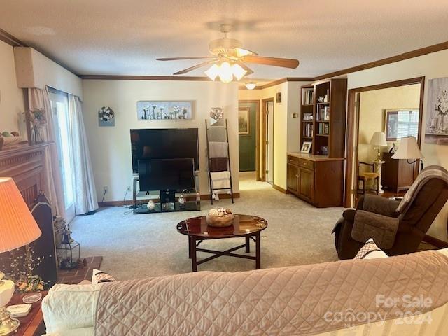 living room with a textured ceiling, light carpet, ceiling fan, and crown molding