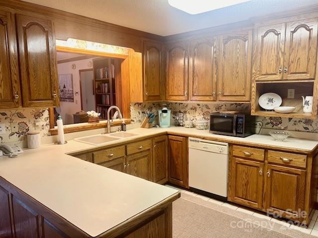 kitchen featuring kitchen peninsula, sink, white dishwasher, and backsplash