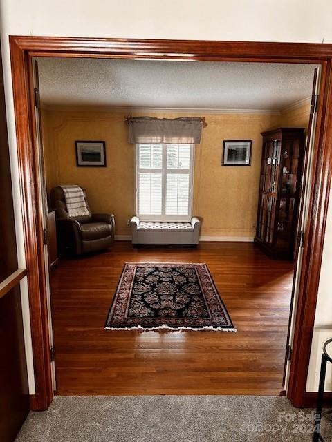 interior space with dark wood-type flooring, a textured ceiling, and crown molding