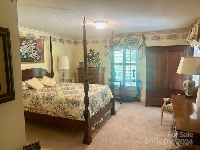 bedroom featuring light colored carpet, a textured ceiling, and crown molding