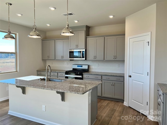 kitchen featuring gas range, a kitchen bar, dark hardwood / wood-style floors, and backsplash