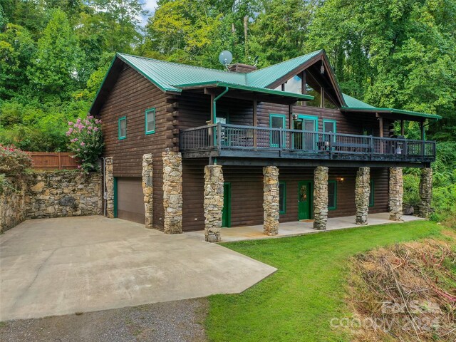 log cabin with a garage, a front lawn, and a balcony