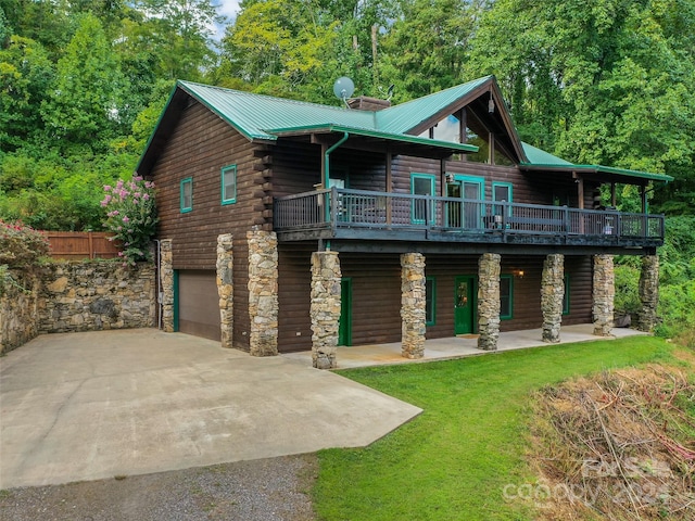 log-style house featuring metal roof, stone siding, concrete driveway, and an attached garage