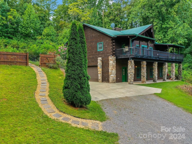 view of front of house featuring stone siding, a front yard, gravel driveway, and metal roof