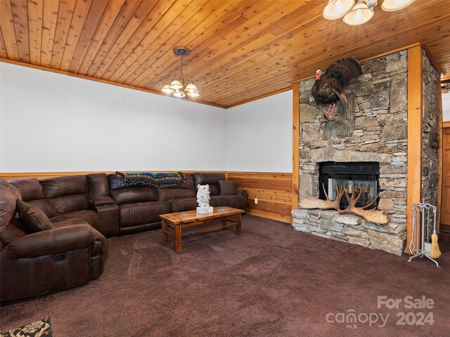 carpeted living room featuring wooden ceiling, a stone fireplace, and an inviting chandelier