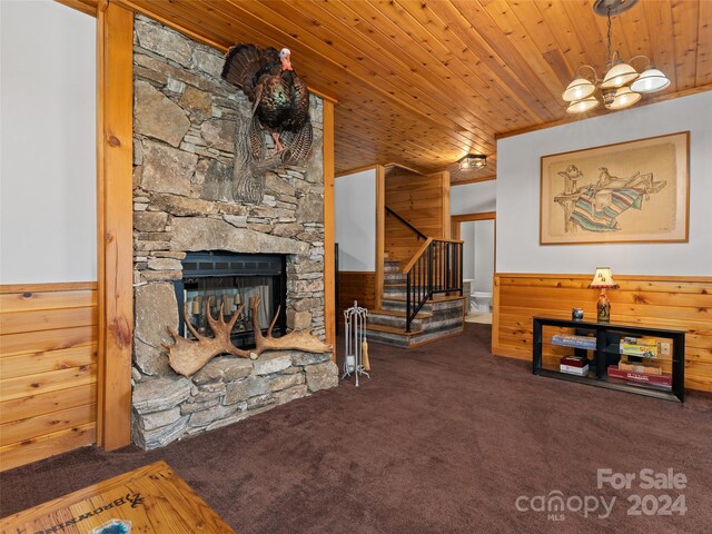 living room with wooden ceiling, a stone fireplace, carpet floors, and wood walls