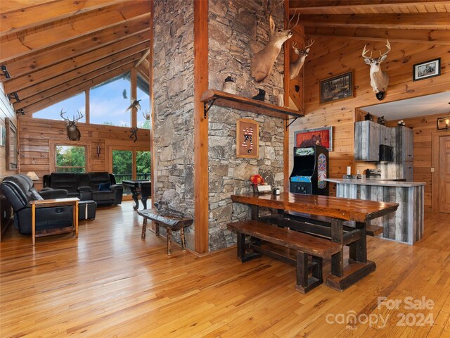 dining area featuring high vaulted ceiling, wood walls, light hardwood / wood-style floors, and wood ceiling