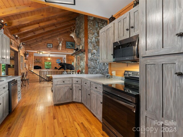 kitchen with vaulted ceiling with beams, light hardwood / wood-style flooring, wooden ceiling, wooden walls, and stainless steel appliances