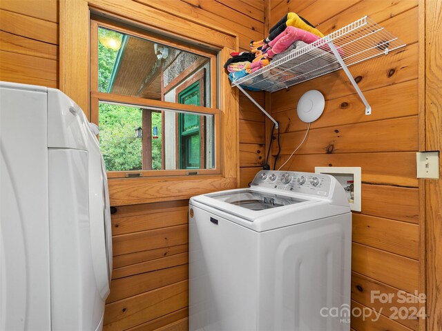 laundry area featuring wooden walls and washer and dryer