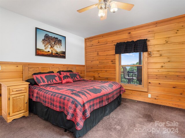 carpeted bedroom with ceiling fan and wood walls