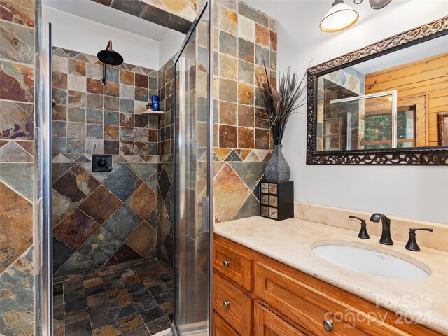 bathroom featuring a shower with shower door and vanity