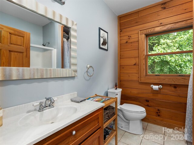 bathroom with a shower with shower door, toilet, vanity, and tile patterned floors