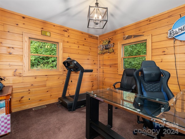 exercise room featuring a notable chandelier, wooden walls, and carpet flooring