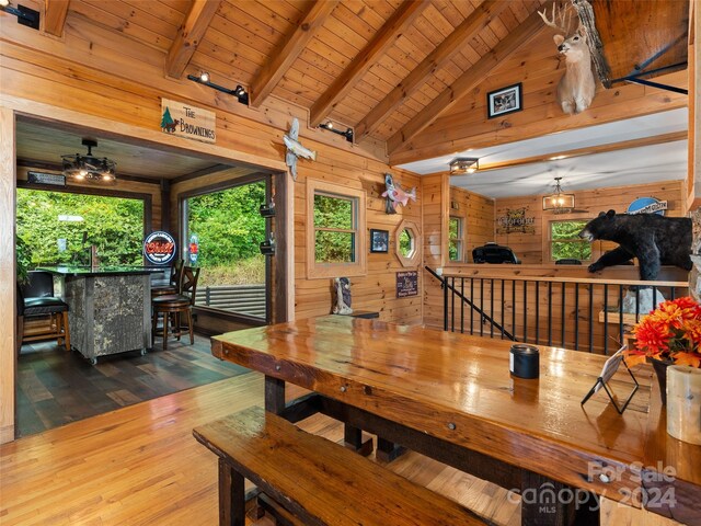 dining space featuring wood walls, hardwood / wood-style flooring, lofted ceiling with beams, and wooden ceiling