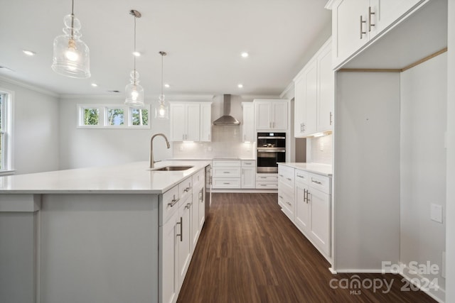 kitchen featuring tasteful backsplash, light countertops, double oven, a sink, and wall chimney exhaust hood