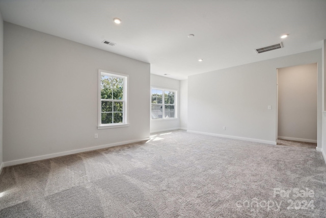 carpeted empty room featuring baseboards, visible vents, and recessed lighting