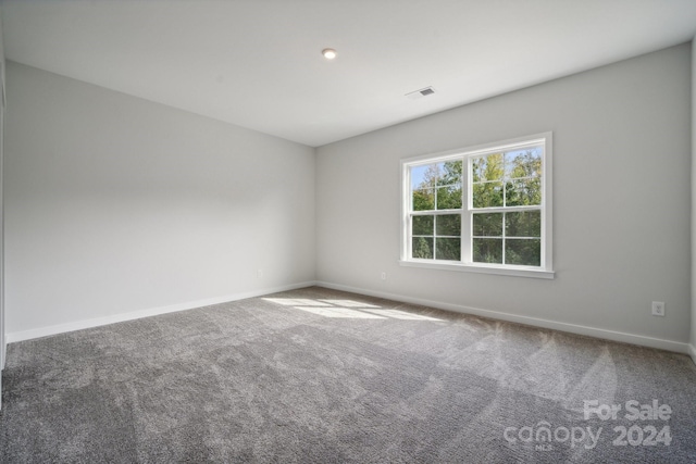 carpeted spare room featuring visible vents and baseboards