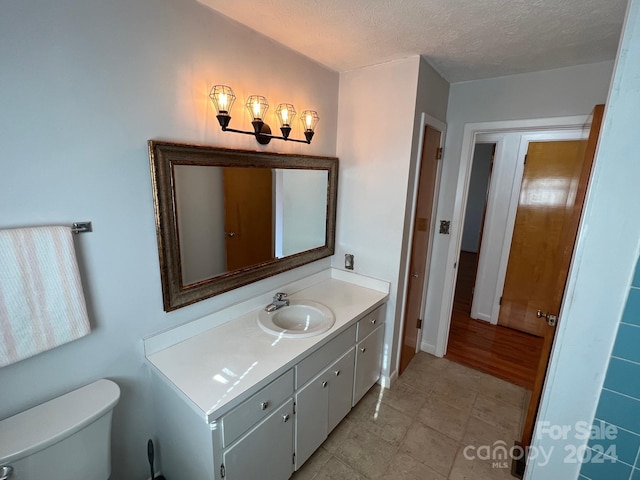 bathroom featuring vanity, a textured ceiling, and toilet