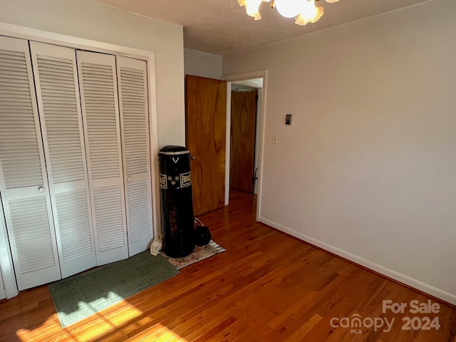 unfurnished bedroom featuring a closet, wood-type flooring, and a notable chandelier