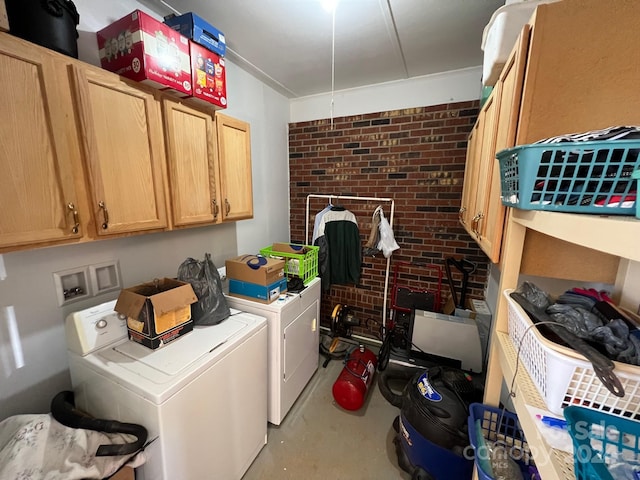 washroom with cabinets, independent washer and dryer, and brick wall