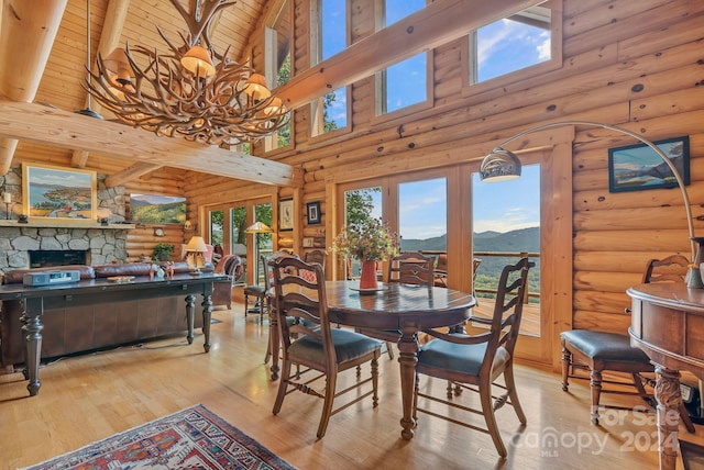 dining space with log walls, light wood-type flooring, a mountain view, beamed ceiling, and high vaulted ceiling