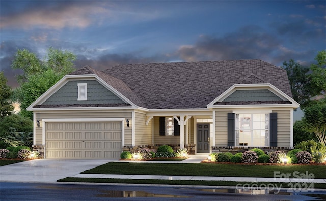 front of house at dusk with driveway, a garage, and a yard