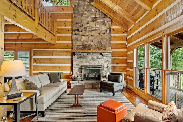 living room with hardwood / wood-style floors, high vaulted ceiling, plenty of natural light, and a stone fireplace