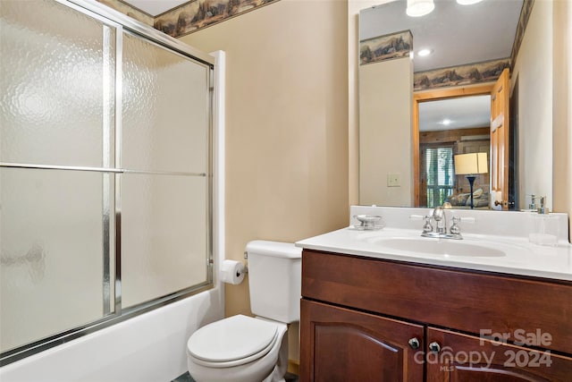 full bathroom featuring vanity, toilet, and combined bath / shower with glass door