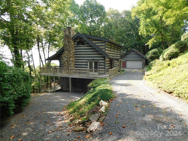 cabin with a wooden deck, a garage, and an outdoor structure