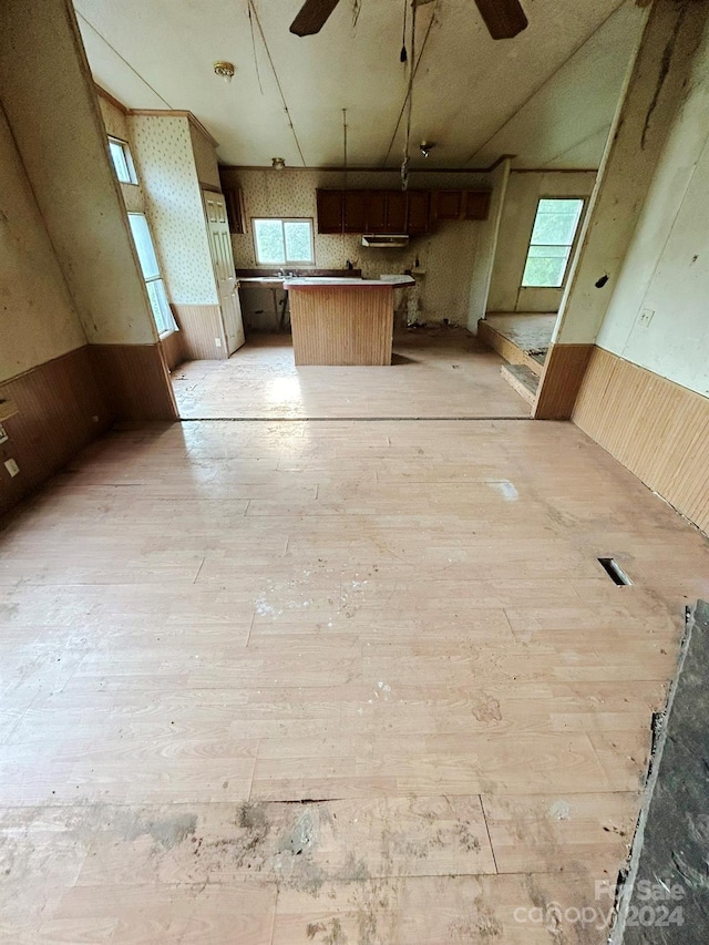 kitchen with light hardwood / wood-style flooring, wood walls, and ceiling fan