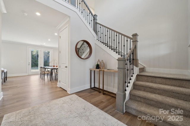 staircase with hardwood / wood-style flooring and ornamental molding