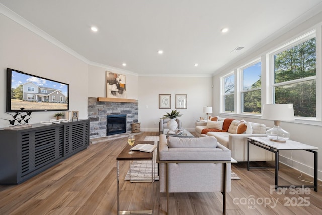 living room with light wood-type flooring, ornamental molding, and a fireplace