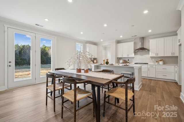 dining area featuring ornamental molding and light hardwood / wood-style floors