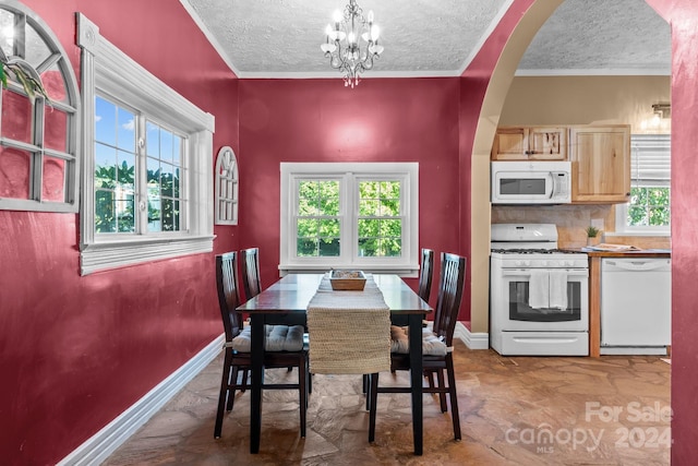 dining area featuring a textured ceiling, crown molding, and a chandelier