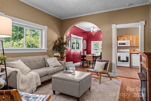 living room with a textured ceiling, a notable chandelier, light tile patterned floors, and crown molding