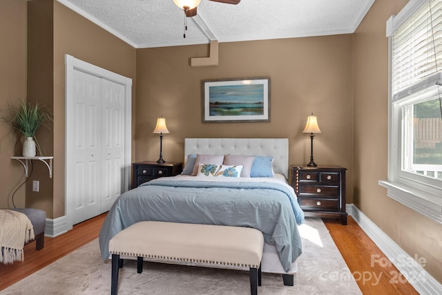 bedroom featuring ceiling fan, light wood-type flooring, a closet, and a textured ceiling