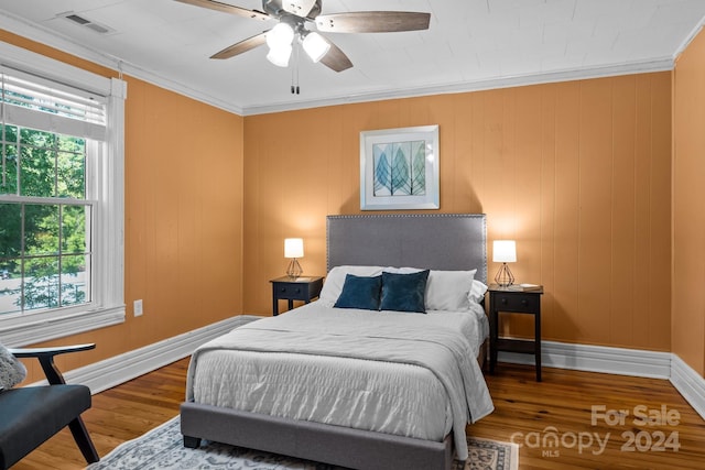 bedroom featuring ceiling fan, wood-type flooring, ornamental molding, and multiple windows