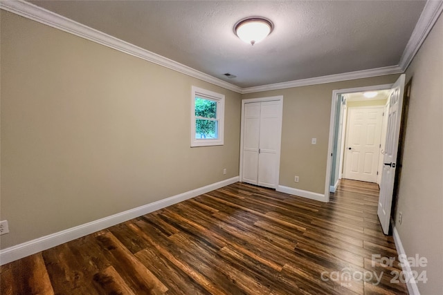 unfurnished bedroom with a closet, dark wood-type flooring, and crown molding