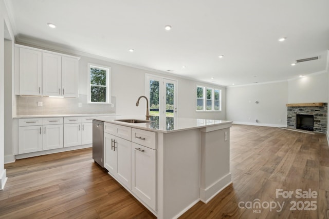 kitchen featuring dishwasher, white cabinetry, sink, a center island with sink, and crown molding