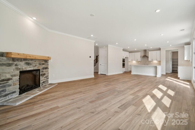 unfurnished living room featuring a fireplace, light hardwood / wood-style floors, and crown molding