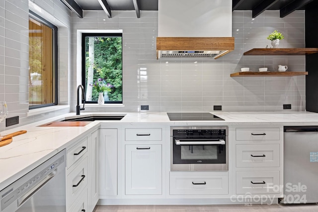 kitchen with appliances with stainless steel finishes, light stone countertops, white cabinets, and tasteful backsplash