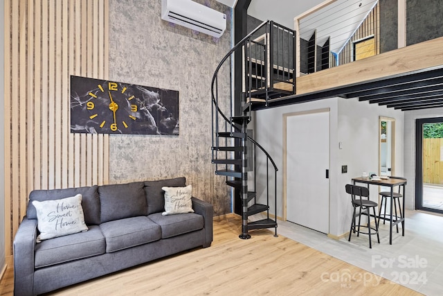 living room with a towering ceiling, a wall unit AC, and wood-type flooring