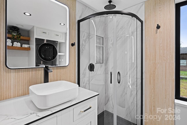 bathroom featuring stacked washer / drying machine, a shower with door, and vanity