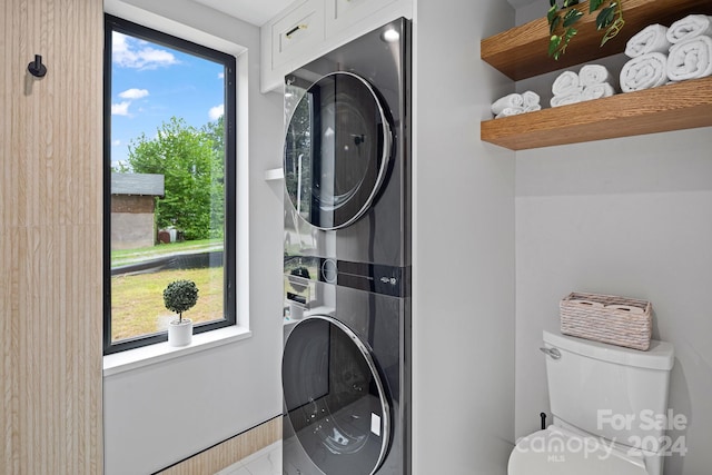 laundry room featuring a wealth of natural light and stacked washing maching and dryer