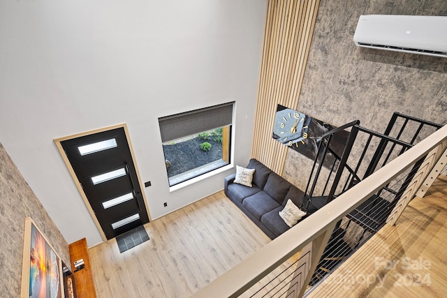 entrance foyer featuring a towering ceiling, light wood-type flooring, and a wall unit AC