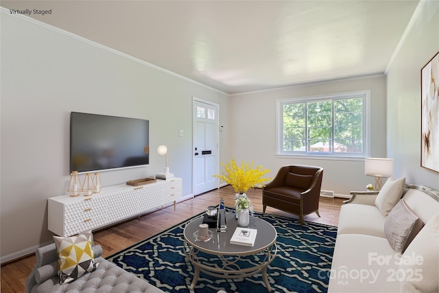 living room featuring crown molding, visible vents, baseboards, and wood finished floors