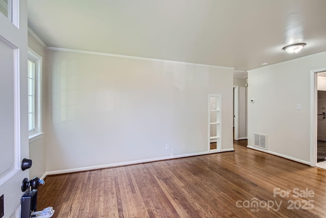 unfurnished room featuring baseboards, crown molding, visible vents, and wood finished floors