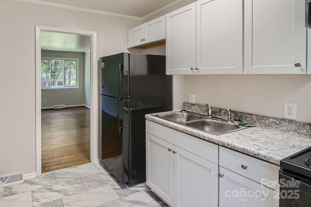 kitchen with a sink, visible vents, white cabinets, ornamental molding, and black appliances