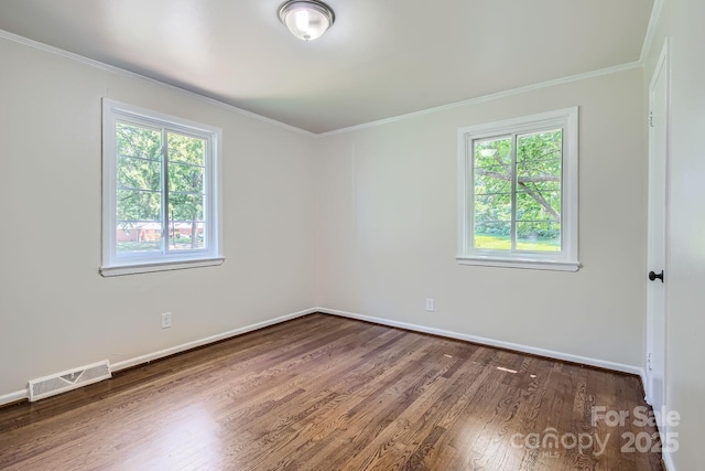 unfurnished room featuring baseboards, visible vents, wood finished floors, and ornamental molding