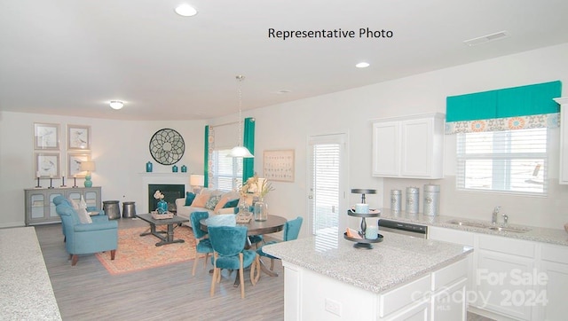 kitchen featuring white cabinets, hanging light fixtures, sink, and light stone counters